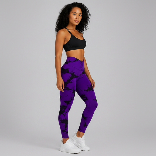 Woman wearing purple tie-dye leggings and black sports bra on a gray background - Aresfit