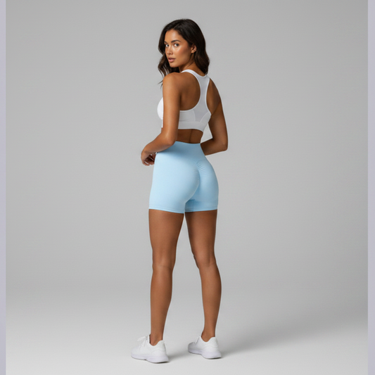 Woman wearing a white sports bra and light blue shorts on a gray background - Aresfit