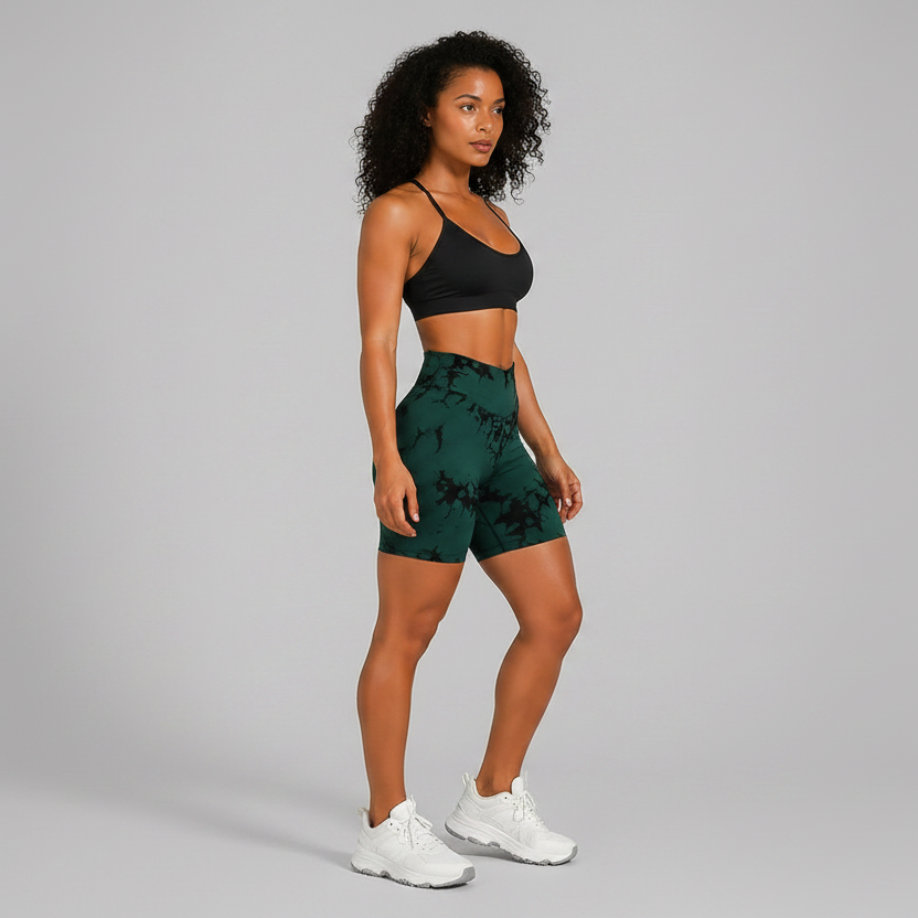 Woman wearing a black sports bra and green tie-dye shorts on a gray background - Aresfit