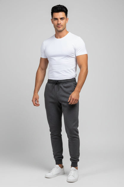 Man wearing a white t-shirt and gray jogger pants on a light gray background