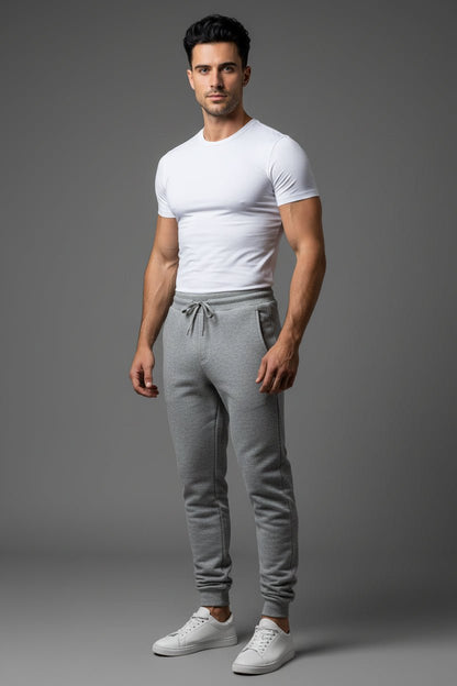 Man wearing a white t-shirt and gray jogger pants on a gray background