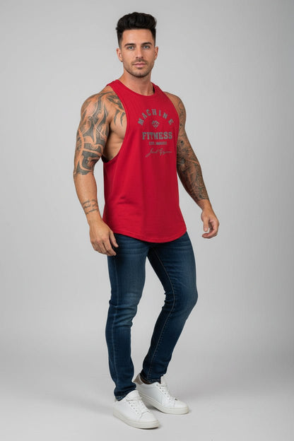 Man wearing a red sleeveless shirt with text, blue jeans, and white sneakers on a gray background