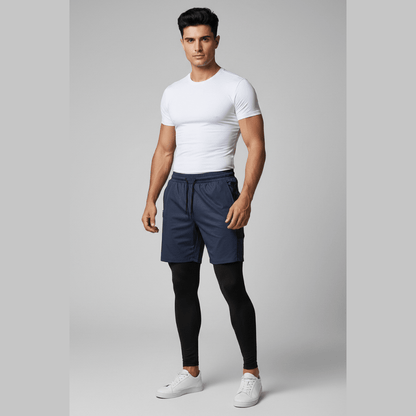 Man wearing a white t-shirt, navy shorts, and black leggings on a gray background
