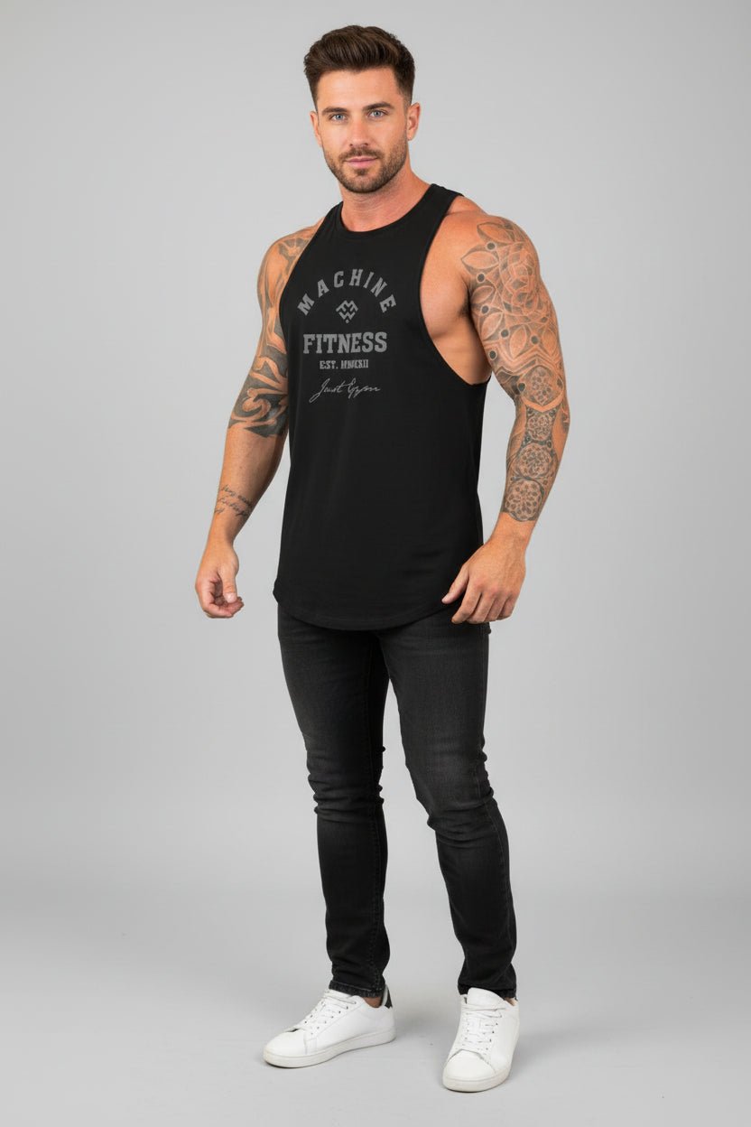 Man wearing a black tank top with text and black pants on a gray background
