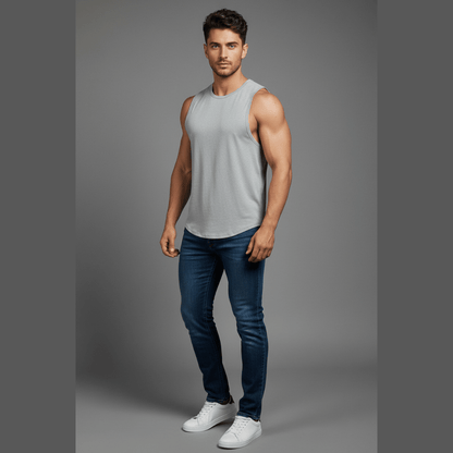 Man wearing a gray tank top and blue jeans on a gray background