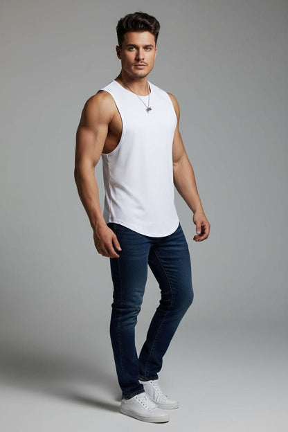 Man wearing a white tank top and blue jeans on a gray background