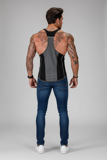 Man wearing a black and gray tank top and blue jeans on a gray background