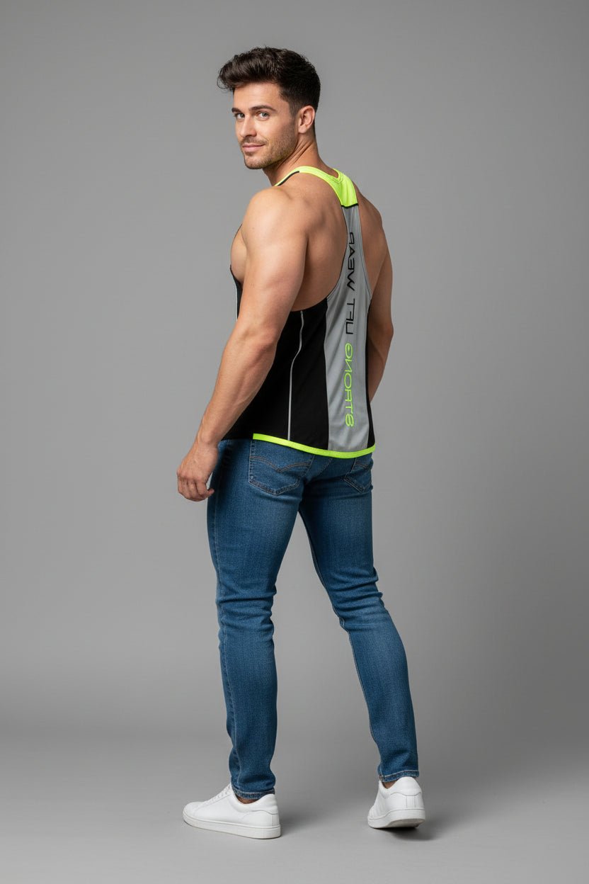 Man wearing a black tank top with green accents and blue jeans on a gray background