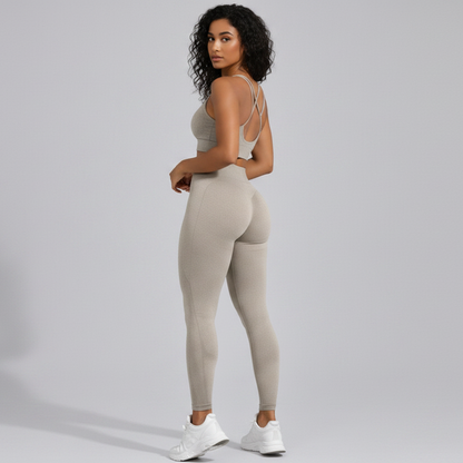 Woman wearing a beige seamless sports bra and high waist leggings set from the back on a gray background - Aresfit